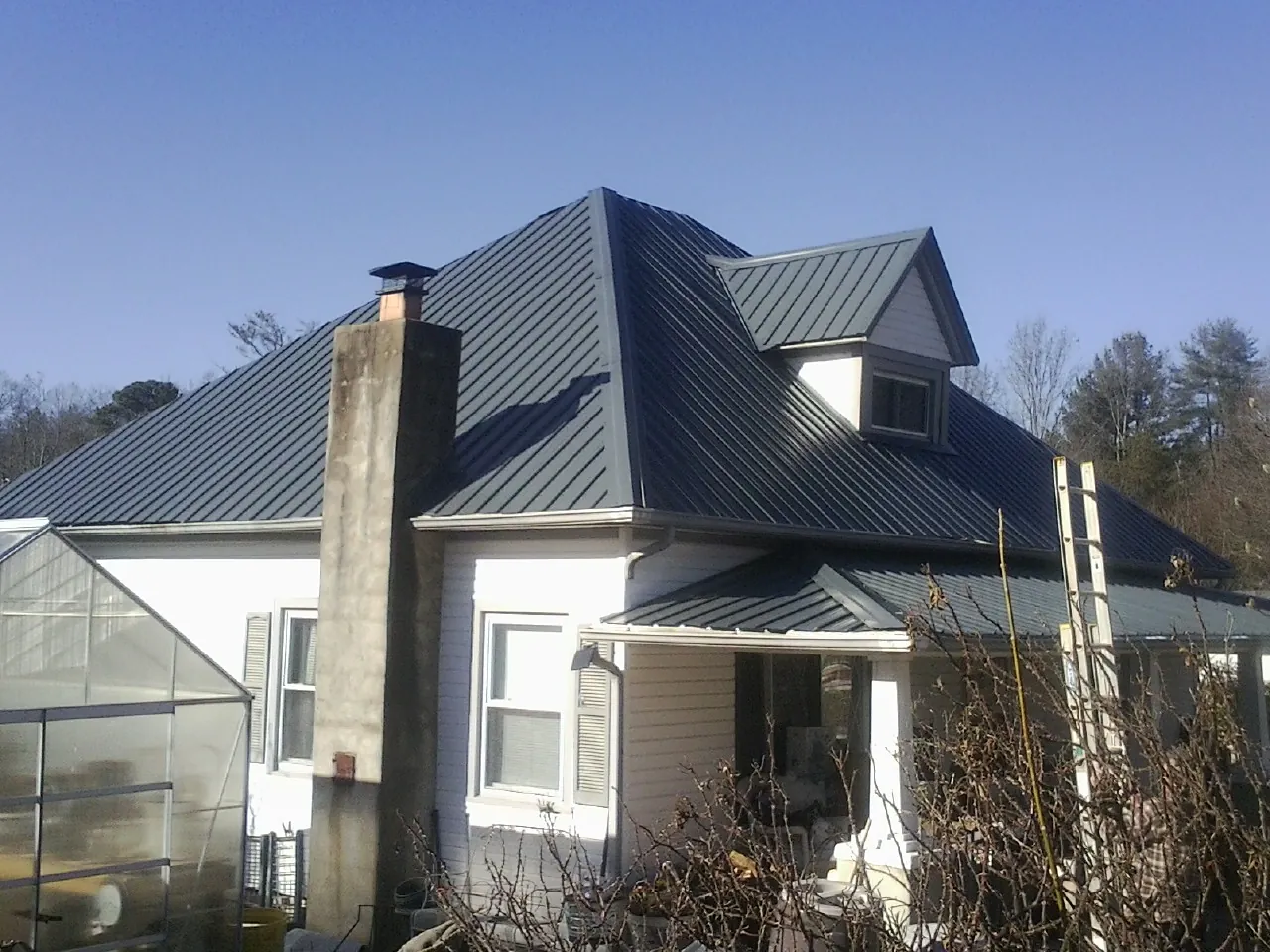 Dark blue standing seam metal roof on a white farmhouse with dormer — Slate & Tile Roof Repair by Roofing Brothers in Tyngsboro