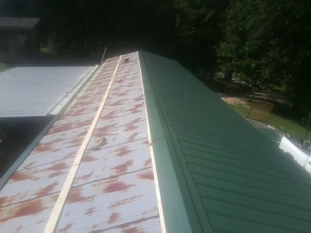 Old rusted panels beside newly installed green metal roofing — Wind Damage Roof Repair by Roofing Brothers in Tyngsboro