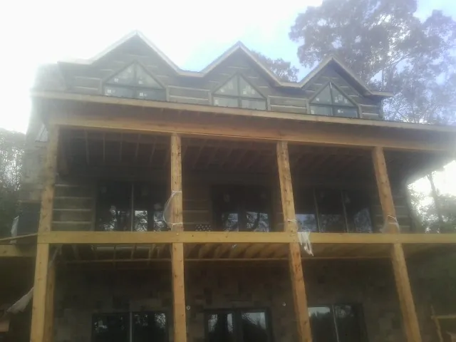 Dormers and porch framing on a large log home under construction — Roof Coating work by our crew in Tyngsboro