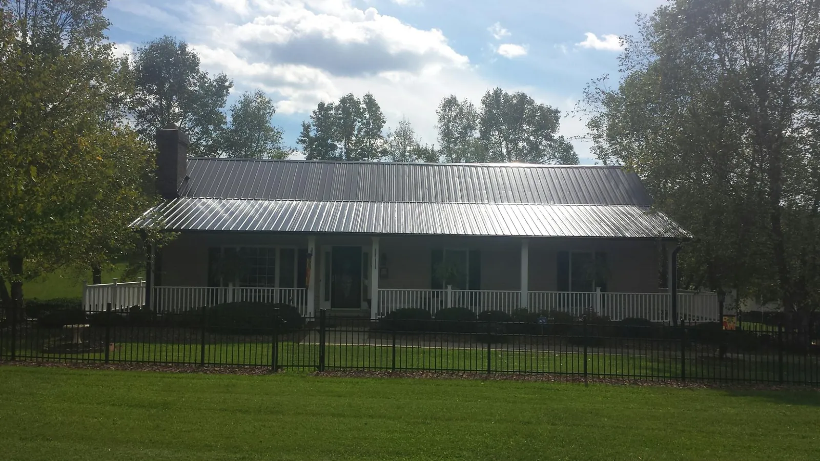 Gray metal roof on a brick ranch with a full width front porch — Gutter Guard Installation work by our crew in Tyngsboro