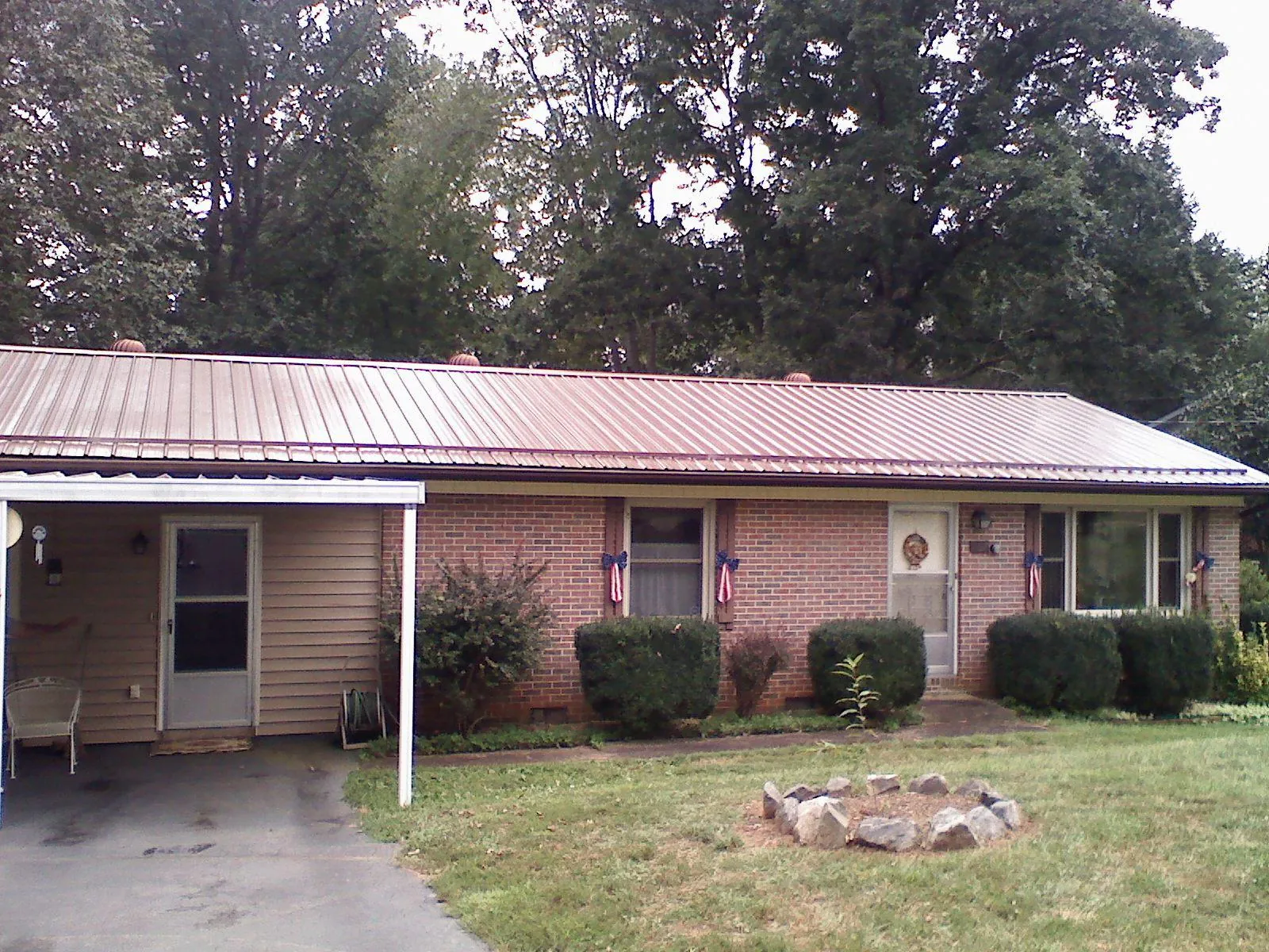 Bronze metal roof and carport on a brick ranch home — Roof Repair work by our crew in Tyngsboro