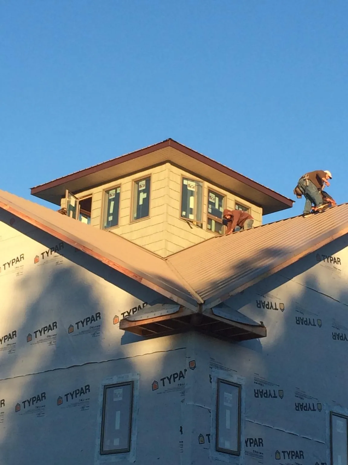 Roofers working around a rooftop cupola on a new metal roof at sunset — Roof Waterproofing in Tyngsboro by Roofing Brothers
